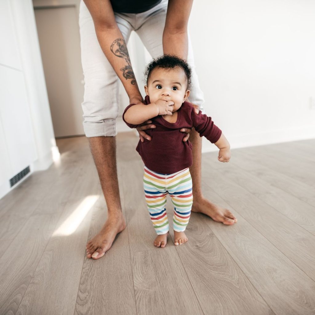 parent helping small child walk across vinyl flooring
